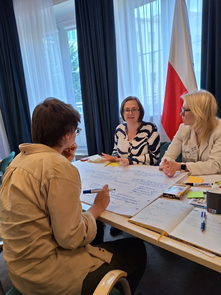 grupa osób pracująca warsztatowo przy stolikach